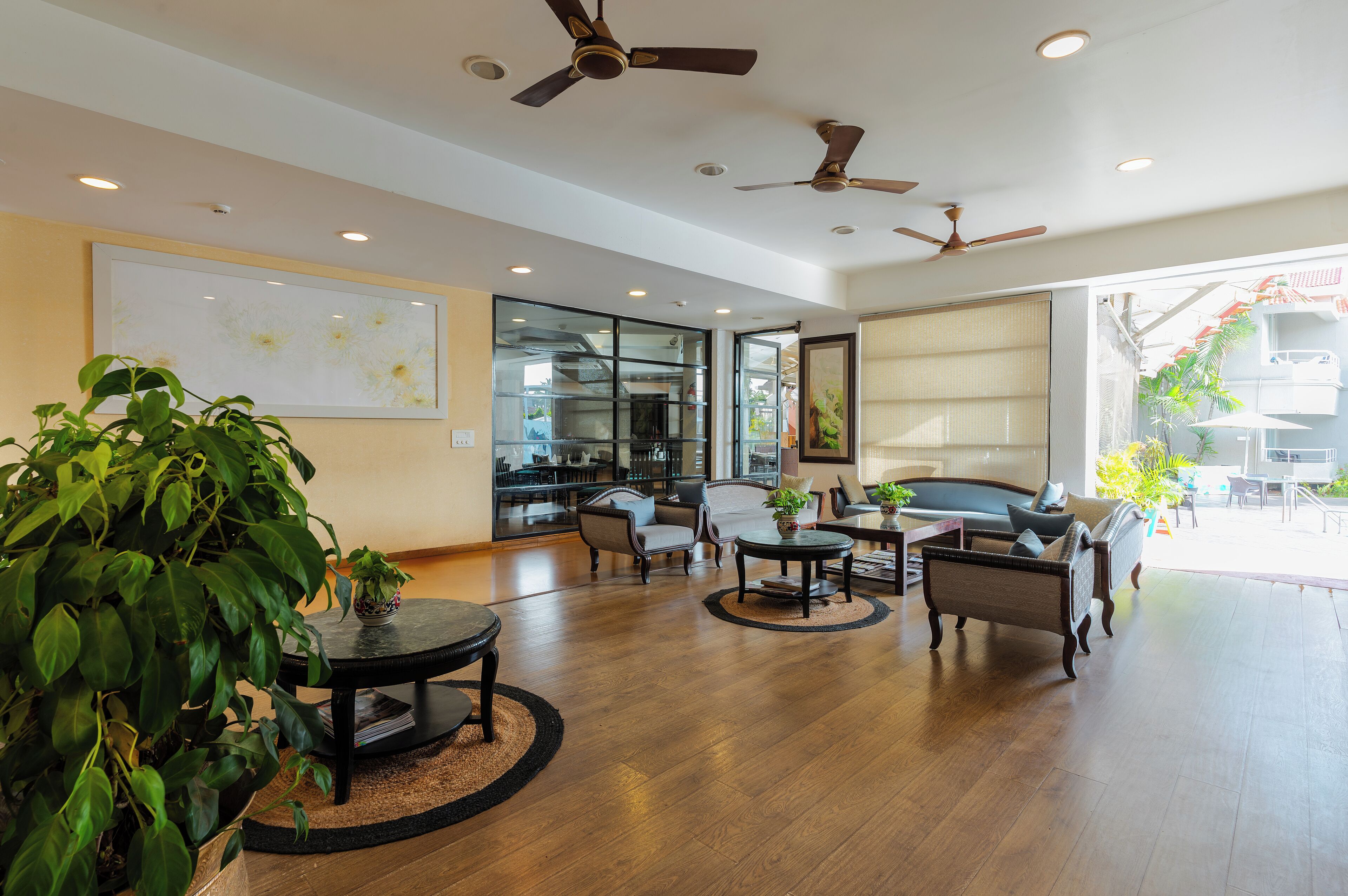 A spacious lobby with modern furniture, ceiling fans, and large windows allowing natural light.