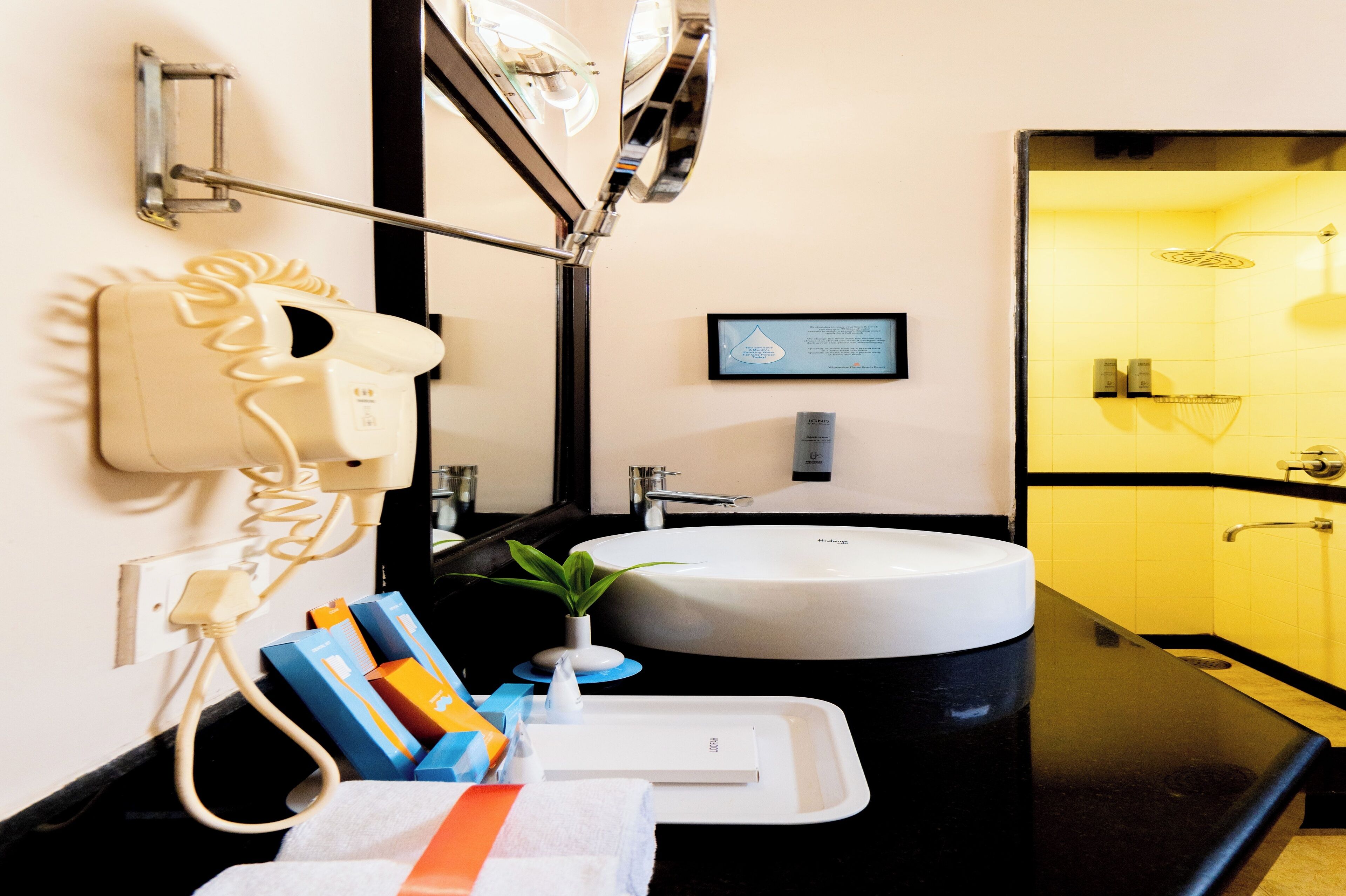 A modern bathroom with a round sink, a hairdryer, and a mirror.