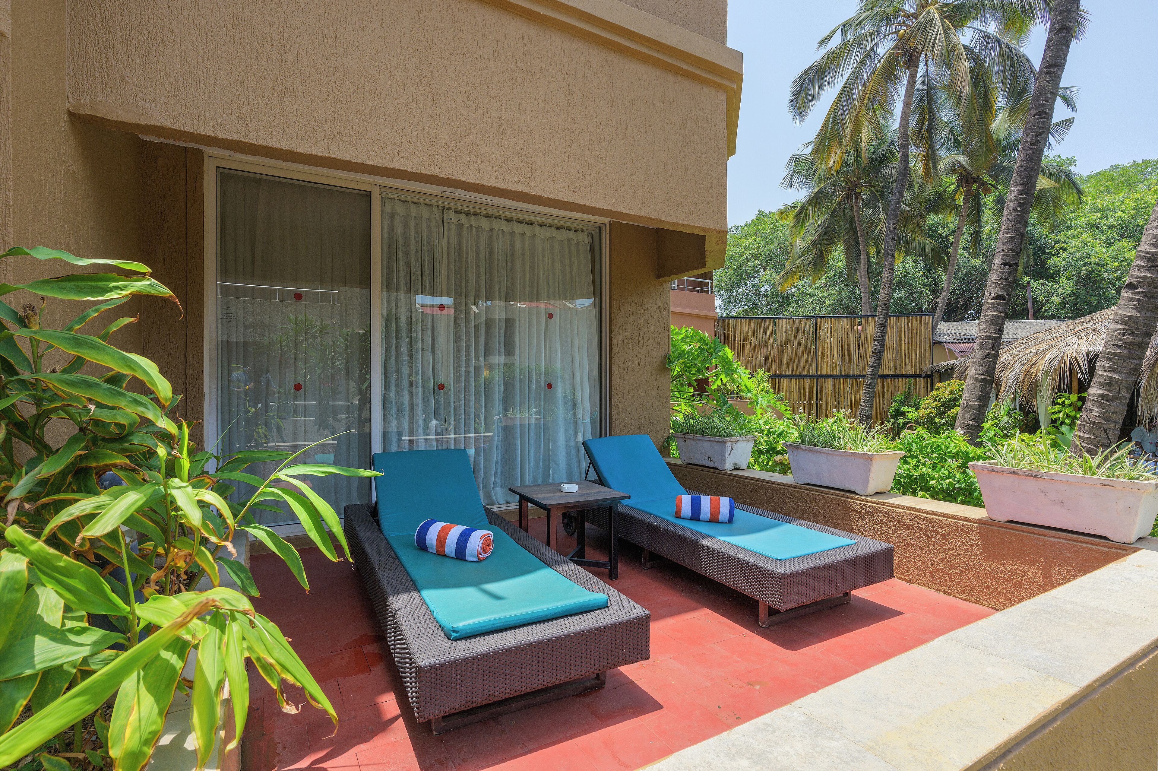 A balcony with two wicker lounge chairs, each with a blue cushion and striped pillow.