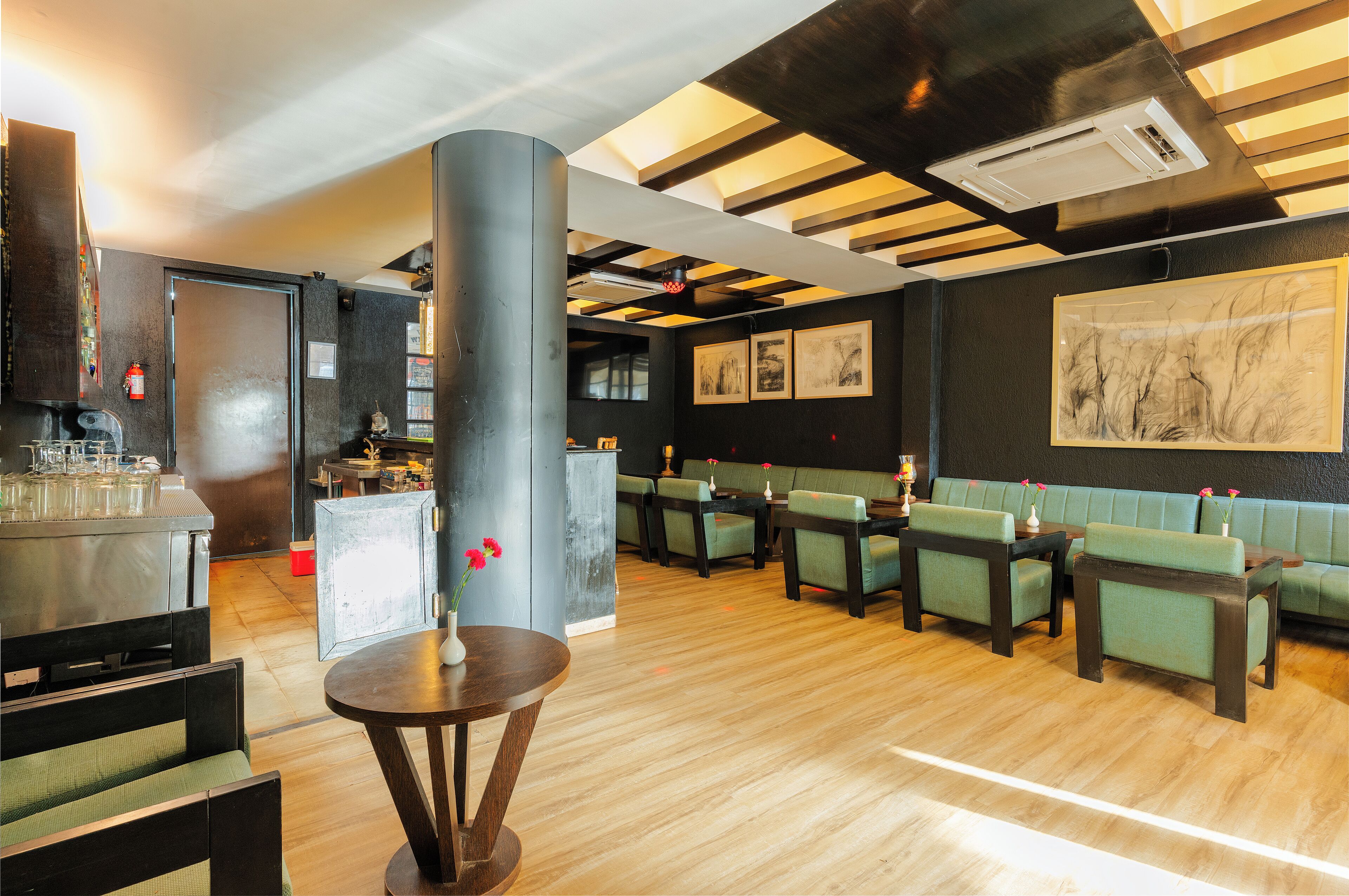 A restaurant with wooden flooring, green upholstered booths, and a bar area with stools.