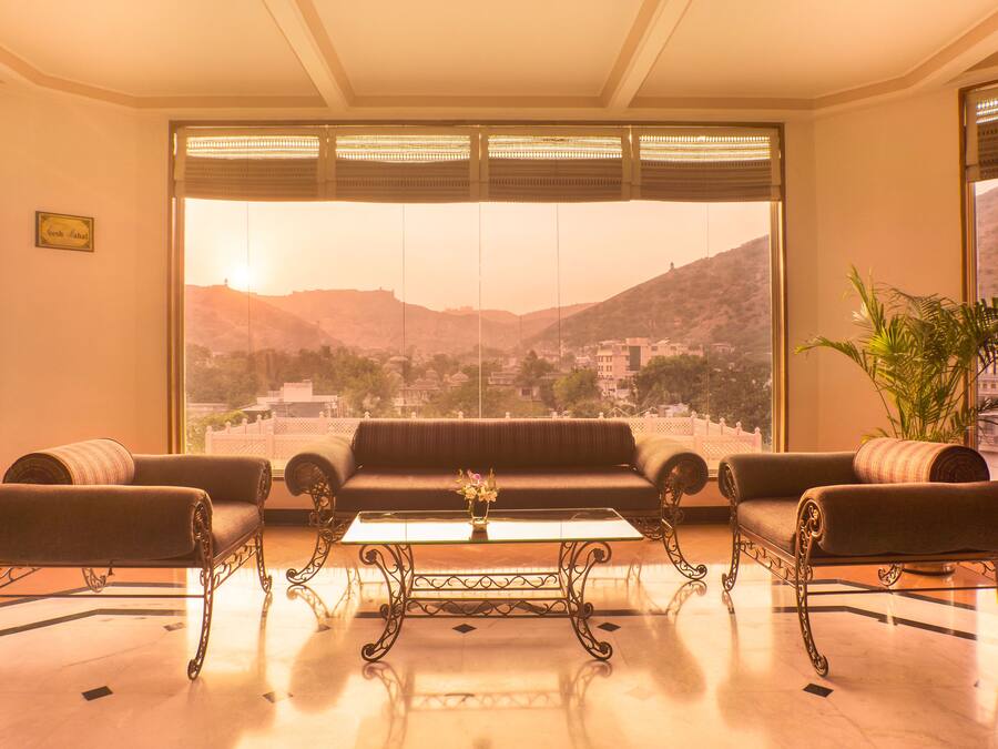 Habitación con un conjunto de sofás, una mesa de centro y vistas a un paisaje montañoso a través de amplios ventanales.