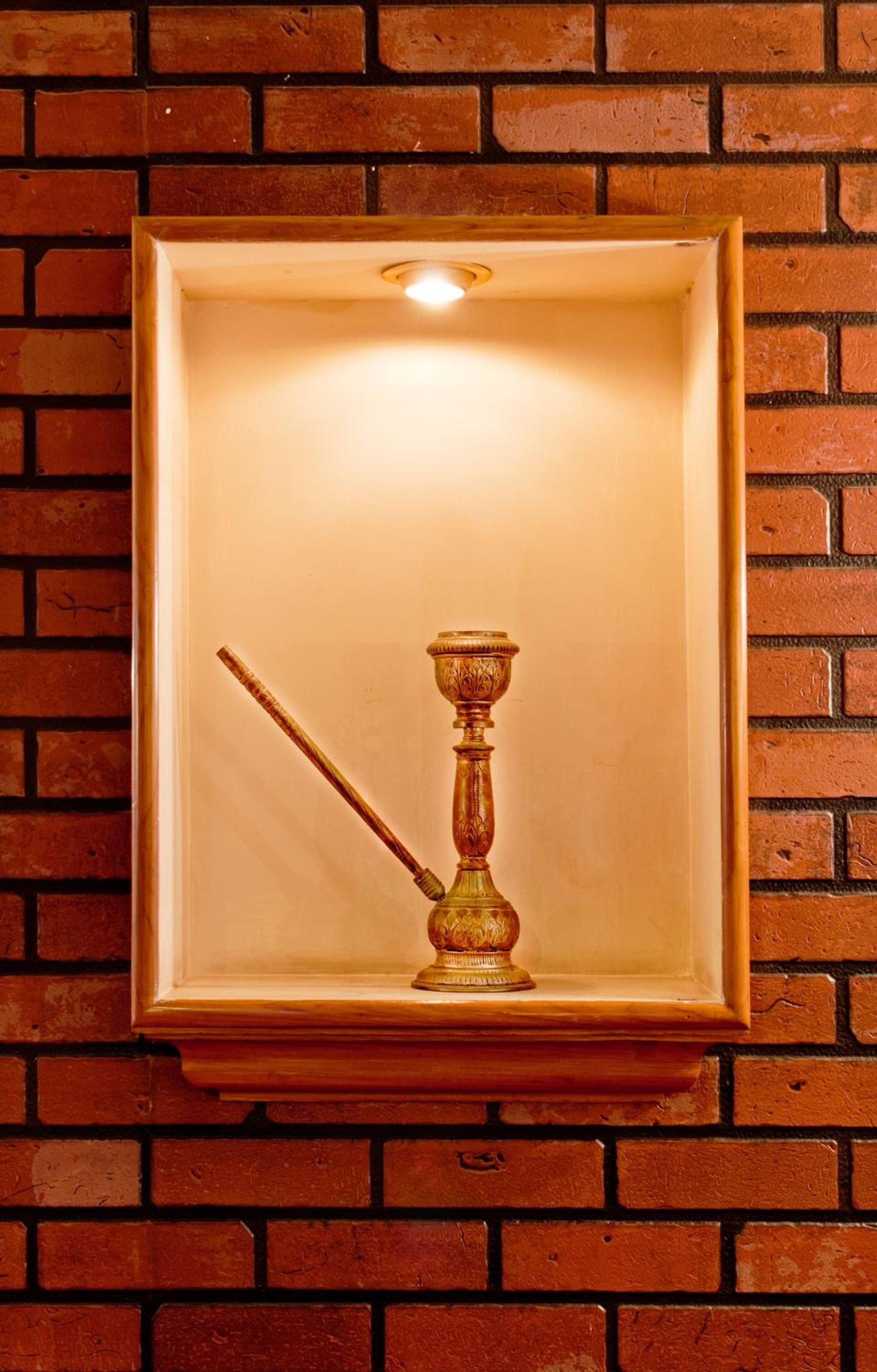 A framed object with a handle and a base, mounted on a brick wall.
