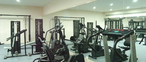 A gym with various exercise equipment including treadmills, weight machines, and free weights.