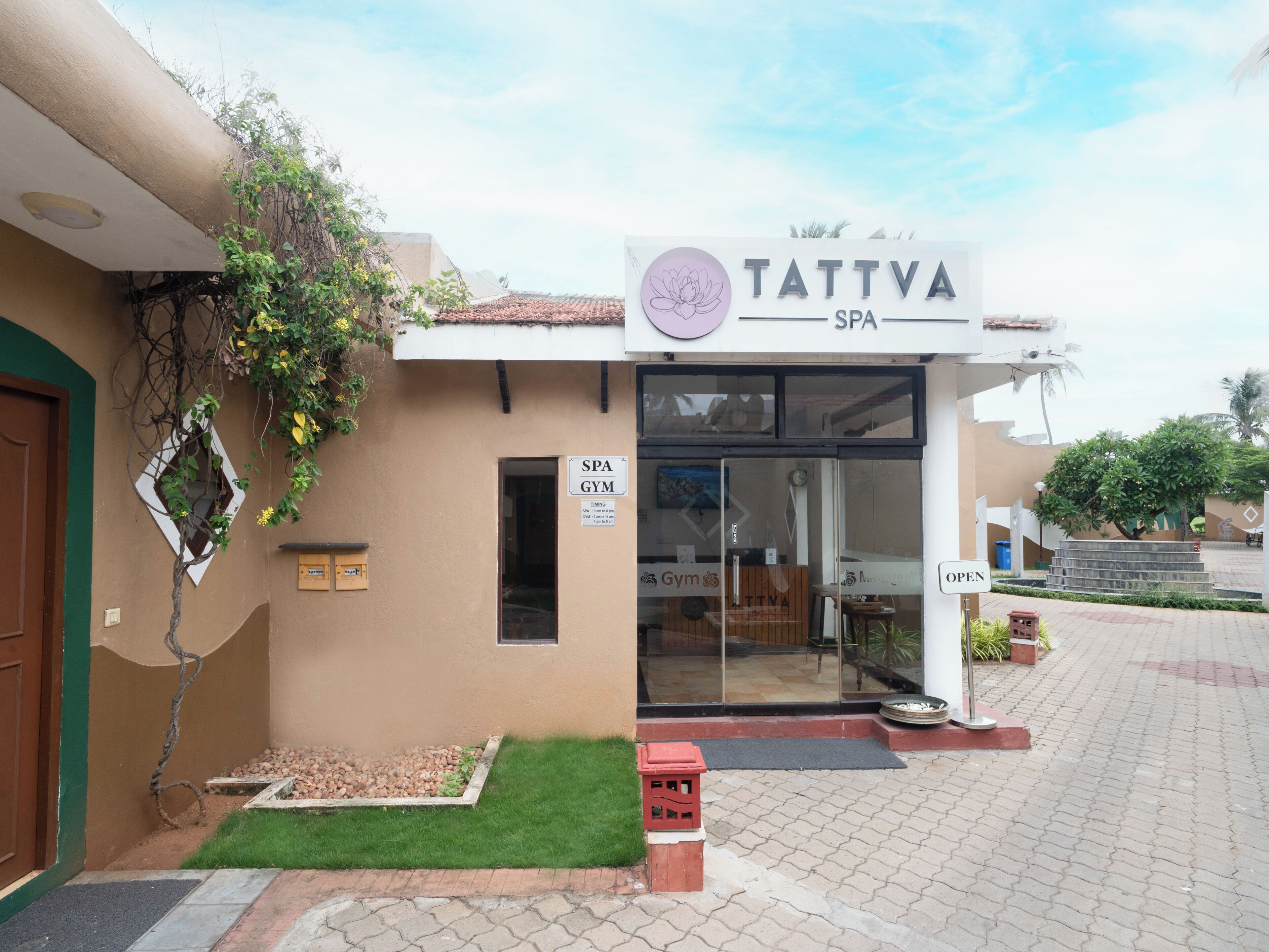 A spa and gym facility with a signboard, a door, and a small garden area.