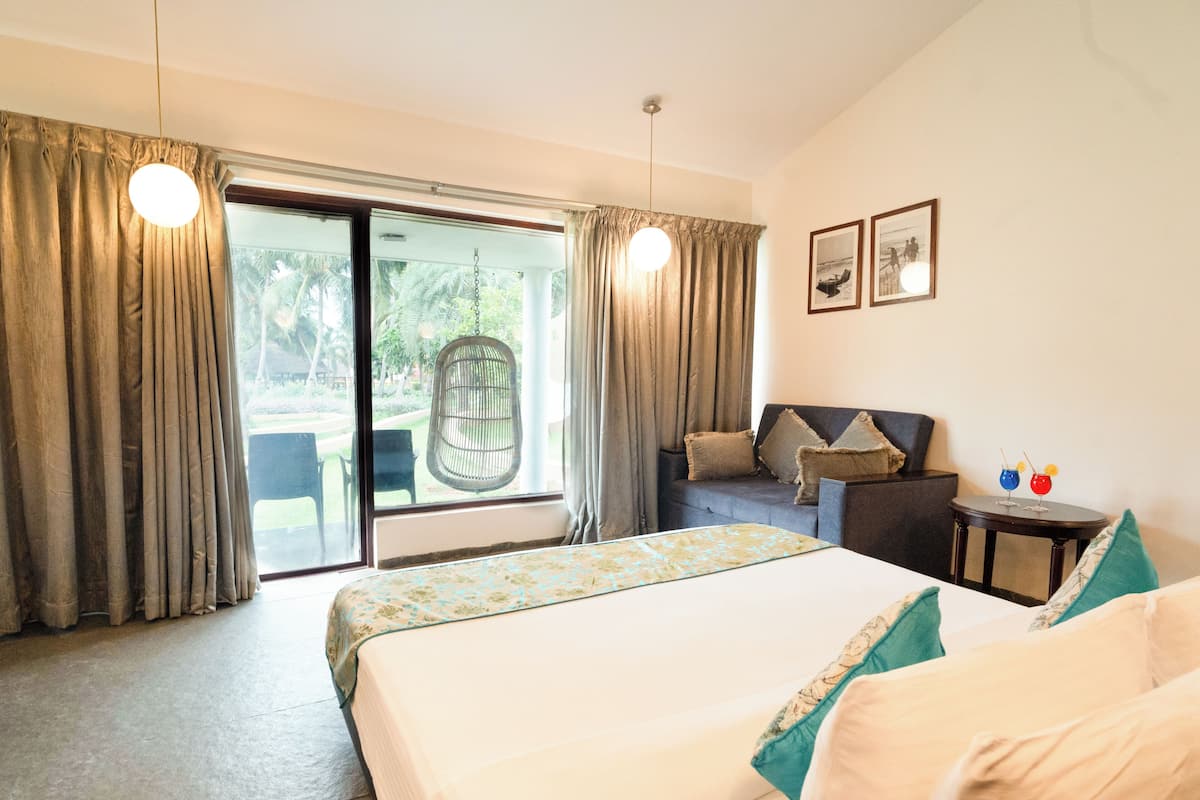 Una habitación de hotel con cama, sofá, una mesita con bebidas y una silla al lado de la ventana.
