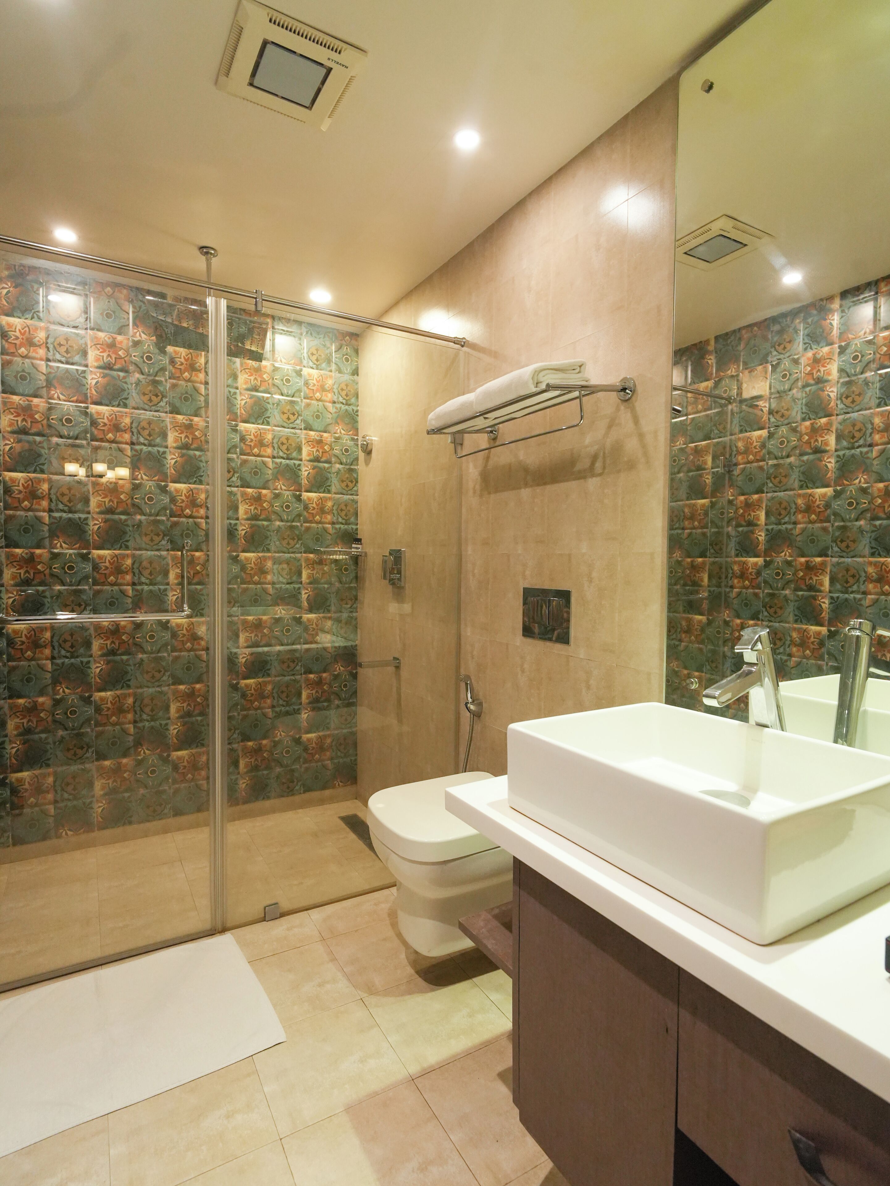 A modern bathroom with a glass-enclosed shower, a white sink, and patterned tiles.