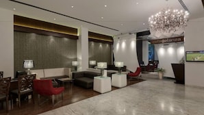 Un vestíbulo moderno con candelabro, sofás y una recepción.