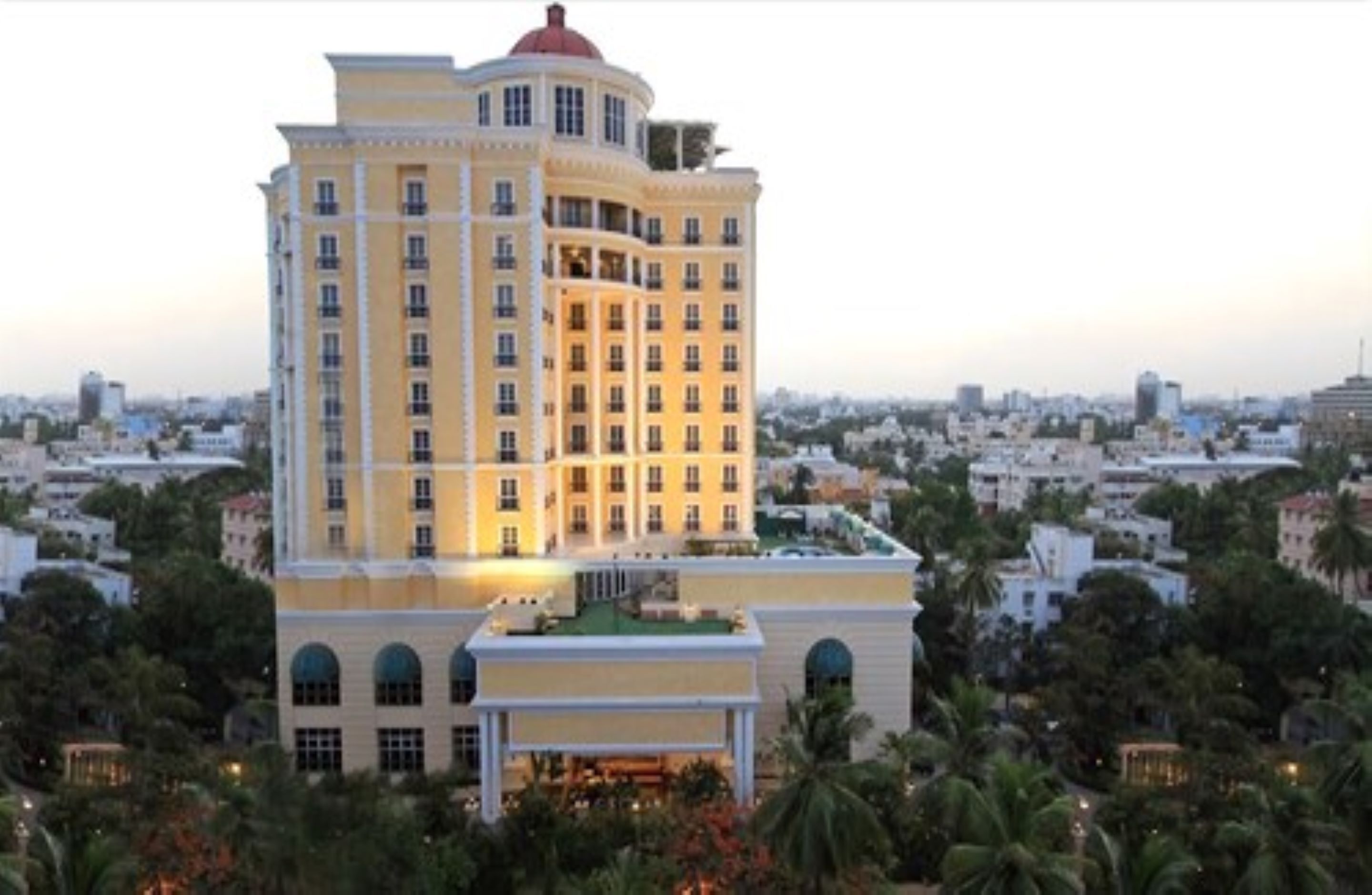 A multi-story hotel with a central courtyard, surrounded by lush greenery.
