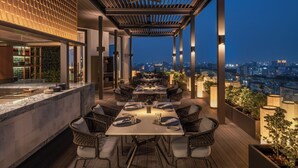 A rooftop restaurant with a terrace, dining tables, and chairs, overlooking a cityscape at night. - The Residency Towers (Chennai)