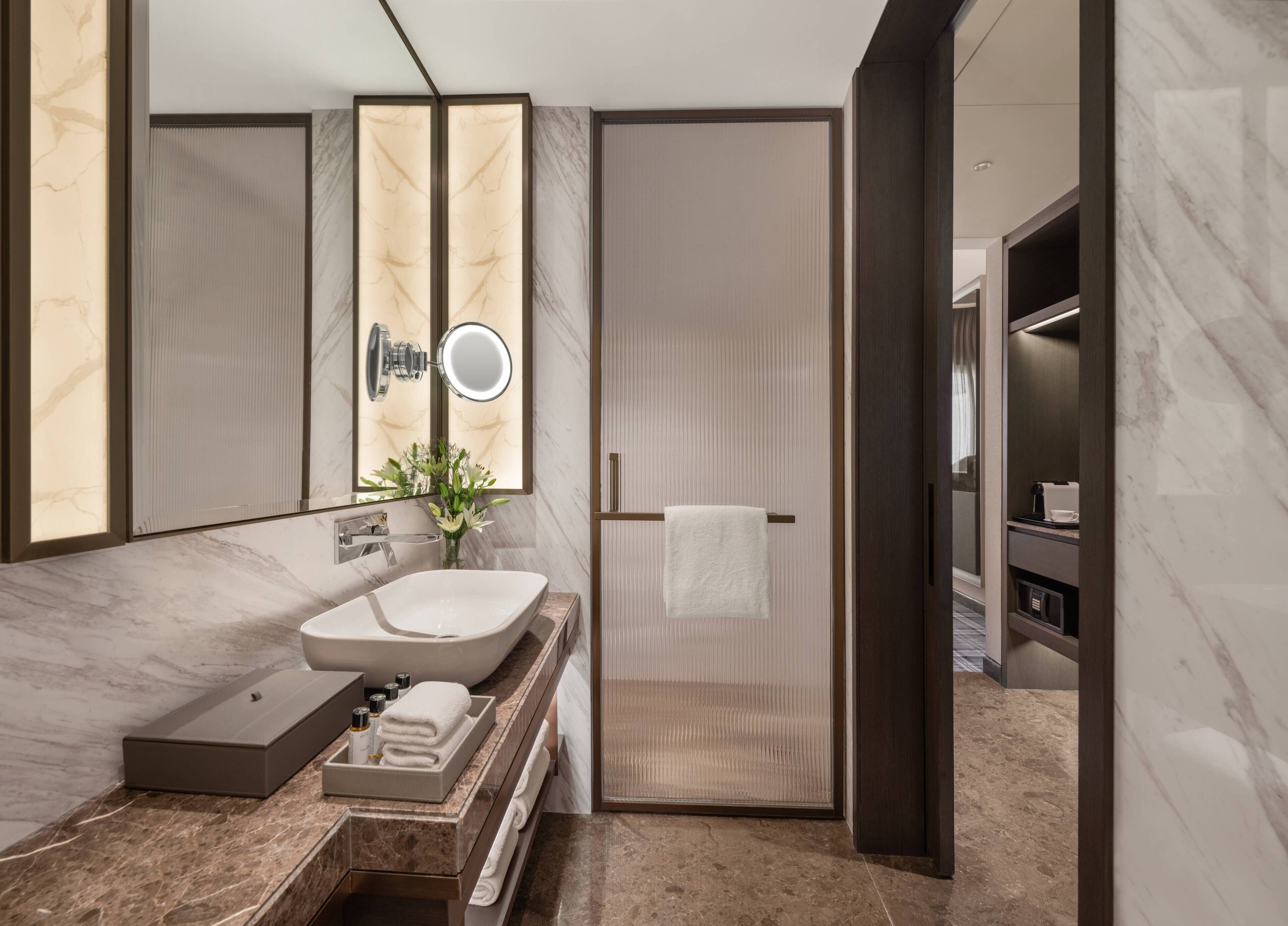 A modern bathroom with a large mirror, a sink, and a shower area.