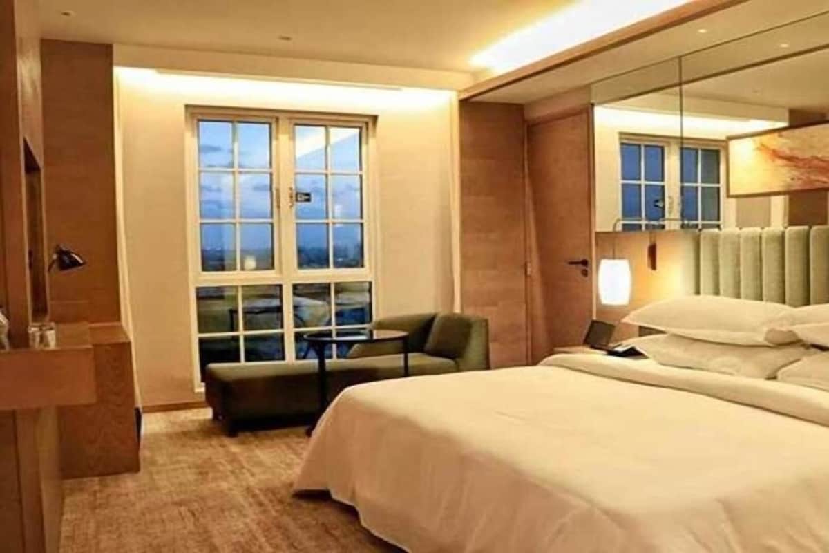 Een hotelkamer met een groot bed, een stoel, een bureau en een raam met uitzicht.