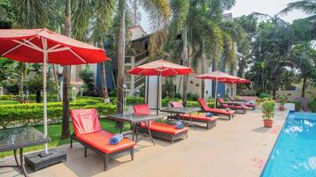Una piscina al aire libre, sombrillas, sillones reclinables de piscina