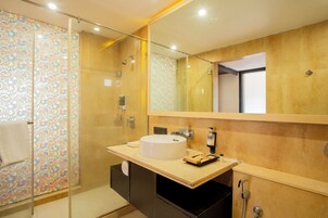 A modern bathroom with a glass-enclosed shower, a large mirror, and a round sink.