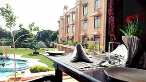 Un comedor con vistas a una piscina y un edificio al fondo.