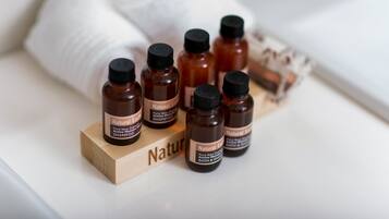 Una serie di piccole bottiglie marroni etichettate 'Natural Earth' su un blocco di legno con la parola 'Nature' parzialmente visibile.