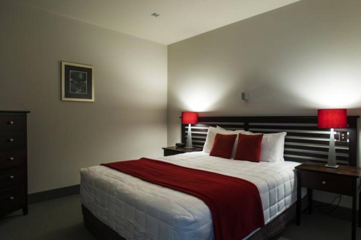 A neatly arranged bedroom with a large bed, two bedside tables, and a dresser.