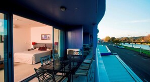 A modern hotel room with a balcony overlooking a river and a bridge. - Emerald Hotel (Gisborne)