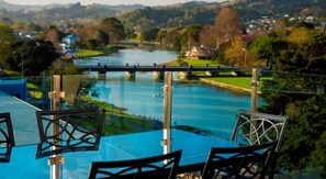 A dining area with a view of a river and a bridge. - Emerald Hotel (Gisborne)