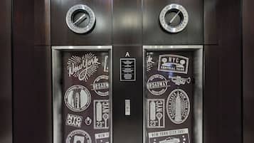 An elevator with NYC-themed decorations, including the Empire State Building and a subway map.