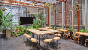 A restaurant with wooden tables and chairs, potted plants, and a brick wall. - Marriott Vacation Club®, New York City (New York)