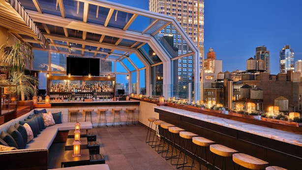 A rooftop bar with a glass enclosure, seating area, bar counter, and city skyline views. - Marriott Vacation Club®, New York City (New York)