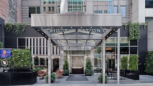 A hotel entrance with a covered entrance, glass doors, and outdoor seating area. - Marriott Vacation Club®, New York City (New York)