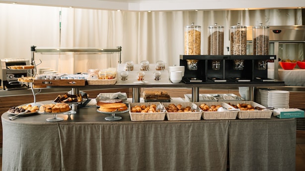 A buffet setup with various food items, including pastries, bread, and cereal. - Hotel Cosmopolitan Bologna (Bologna)