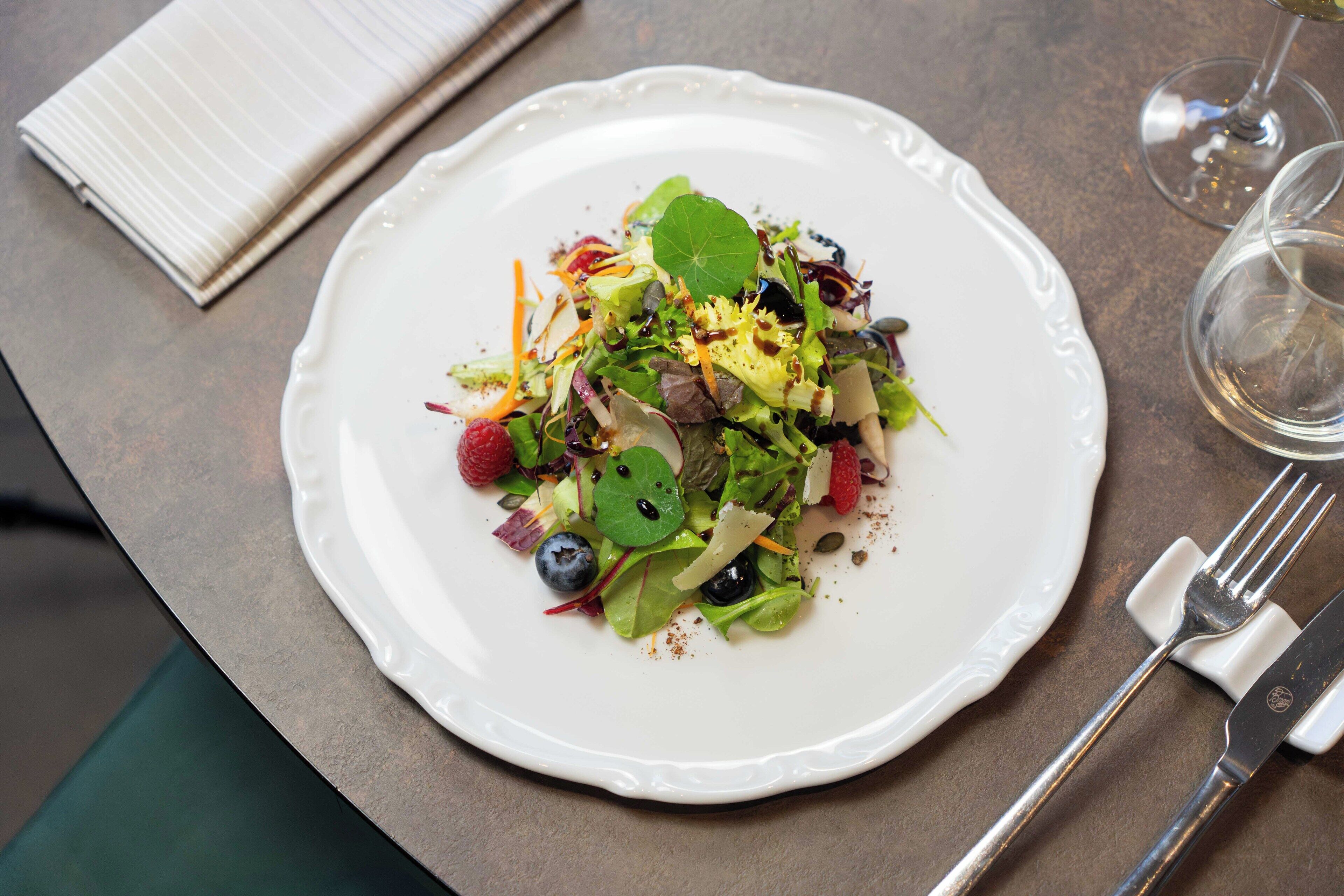 A white plate with a salad on a table.