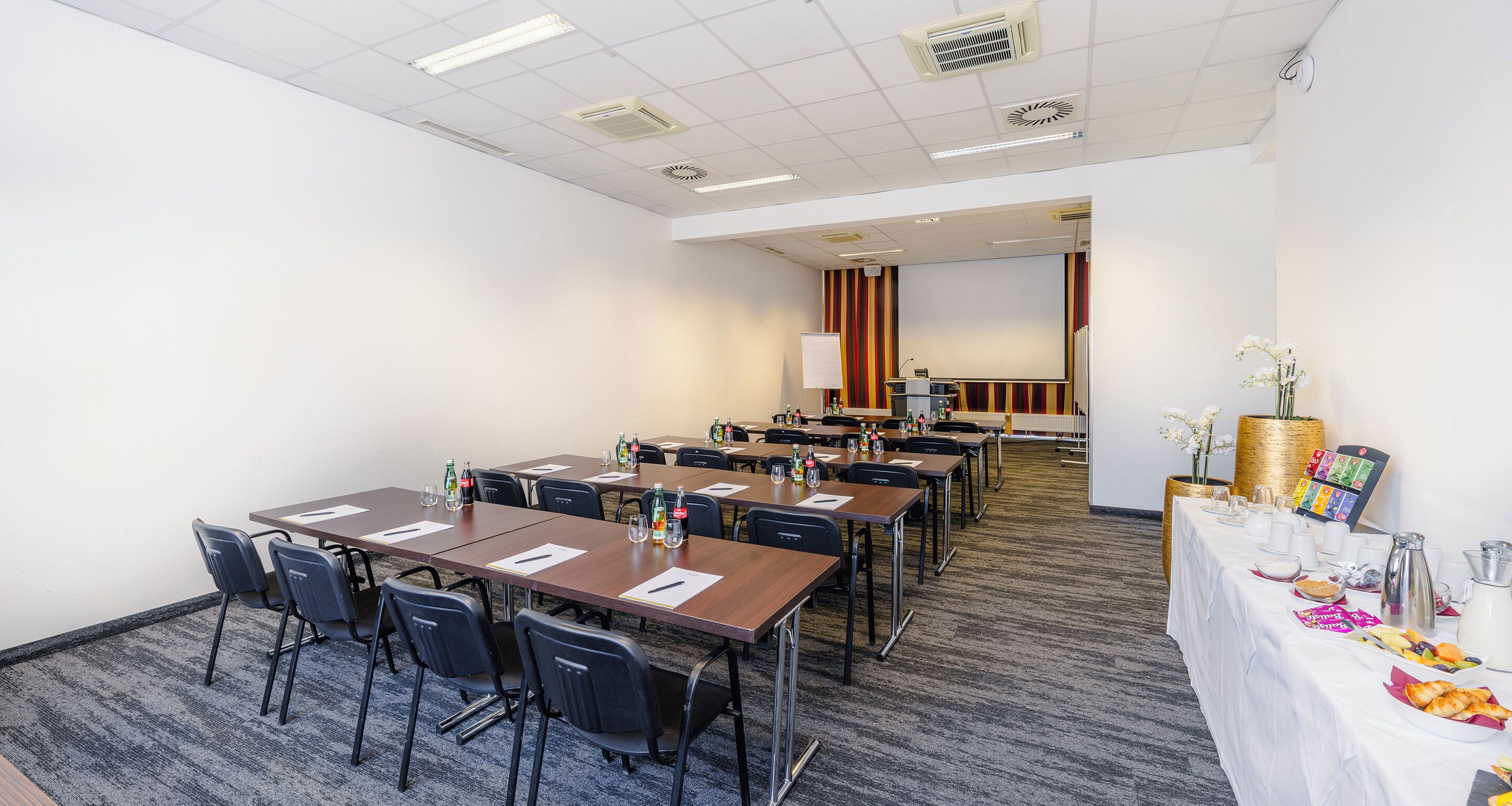 Ein Konferenzraum mit mehreren Tischen, Stühlen und einem Büfett mit Speisen und Getränken.
