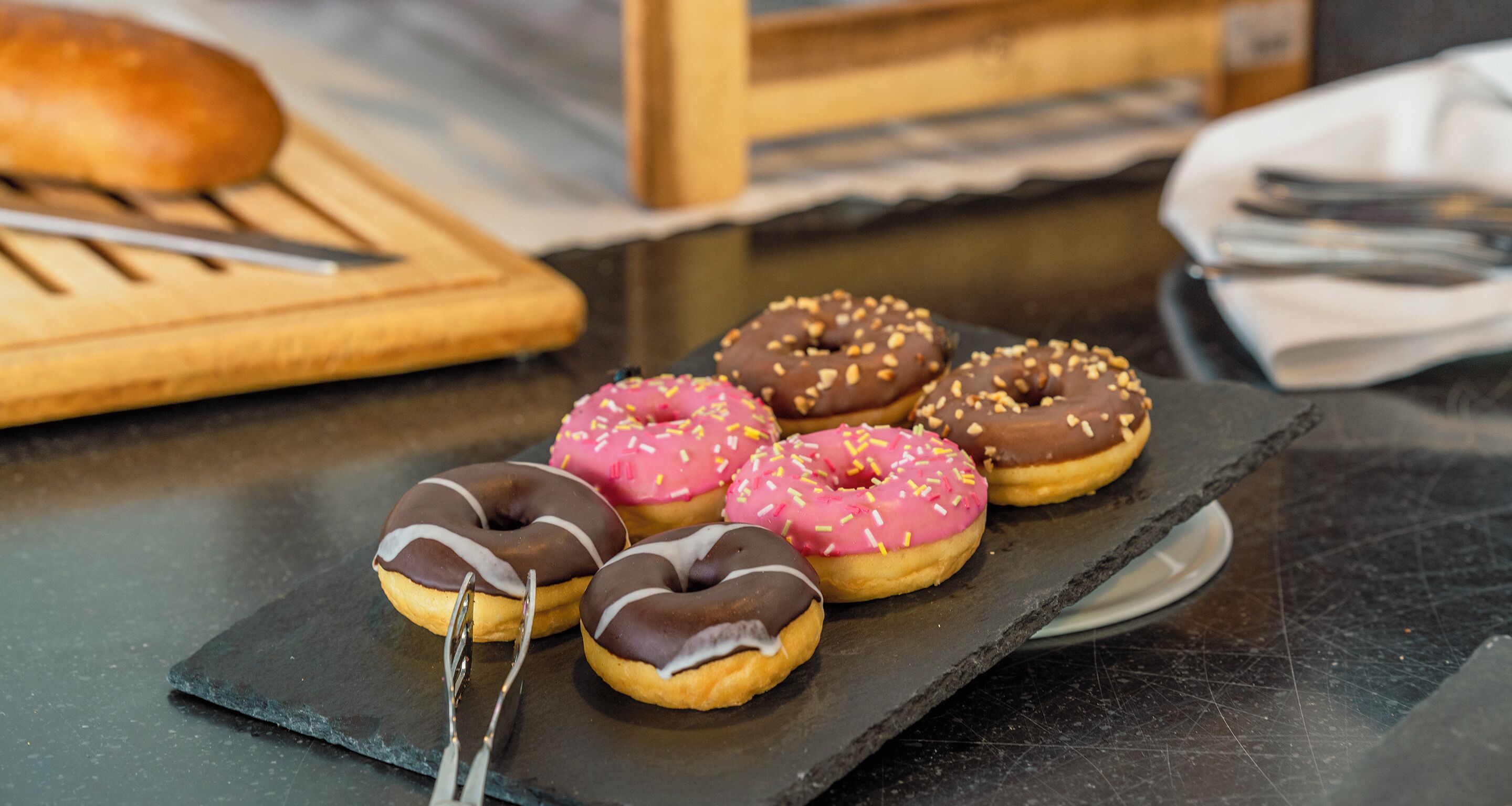 A selection of donuts on a slate board.