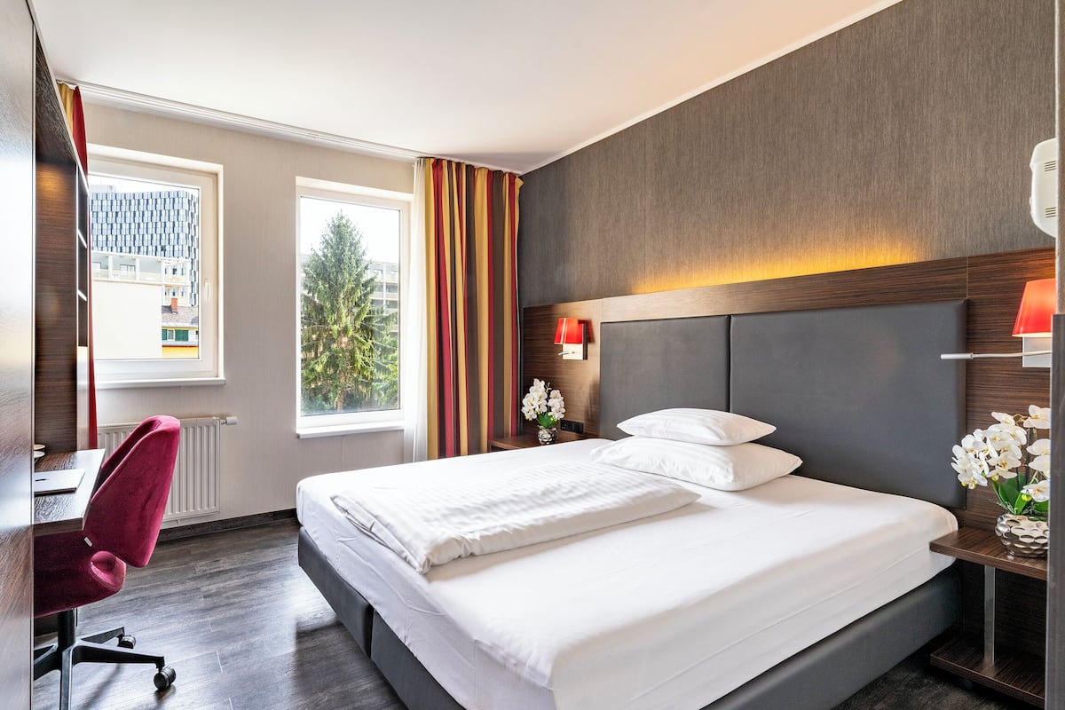 Une chambre d’hôtel avec un grand lit, un bureau et une chaise.