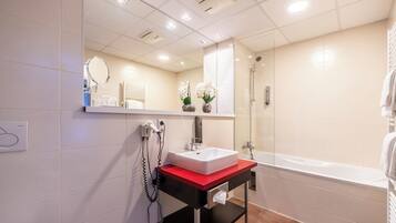 Un baño moderno con un lavabo blanco, una encimera roja, una ducha con mampara de cristal y un espejo sobre el lavabo.