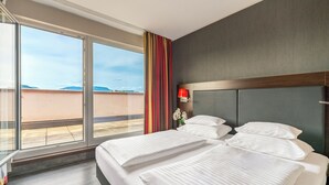 Habitación de hotel con dos camas, un ventanal grande y vistas al exterior.