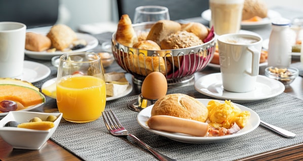 Desayuno con cruasanes, huevos y zumo de naranja sobre una mesa.