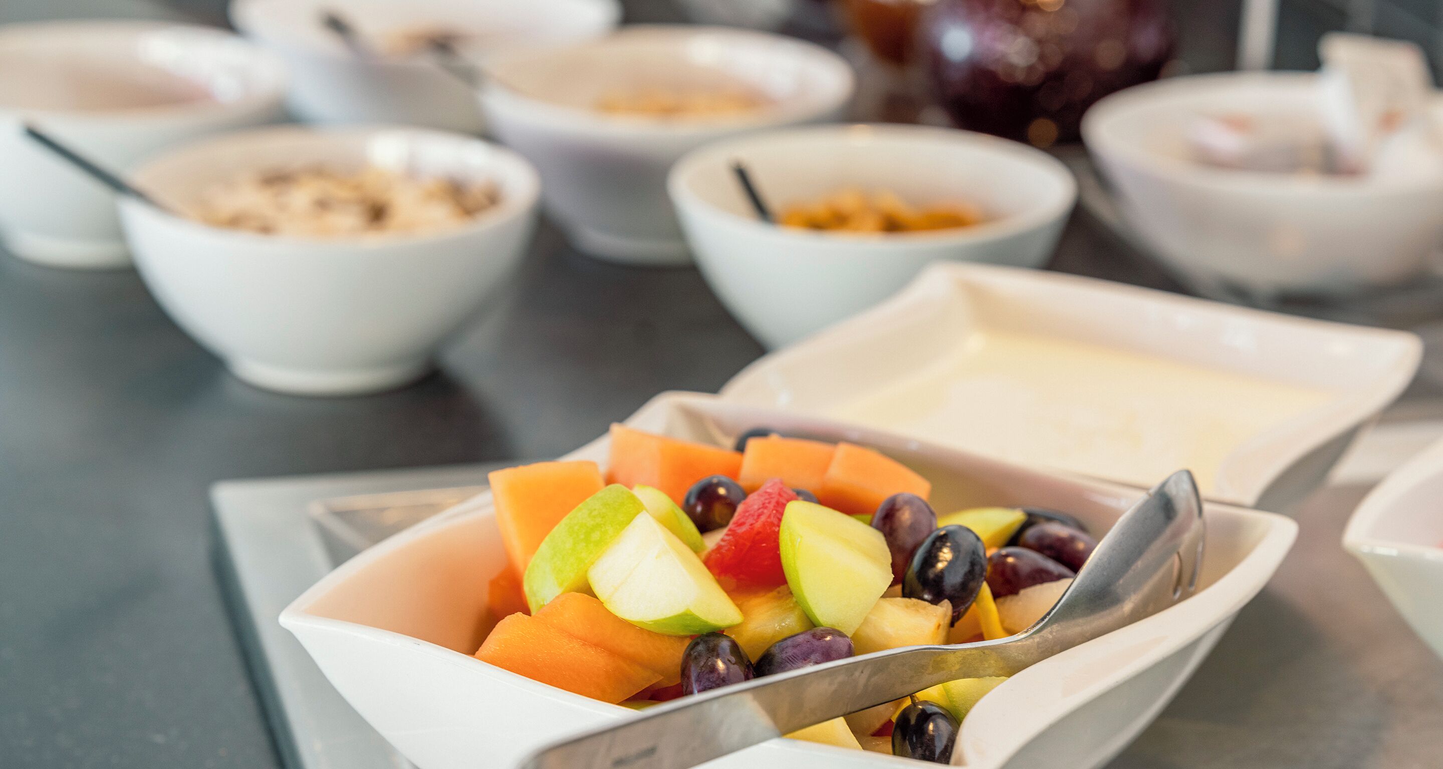 A bowl of fruit salad with a spoon.