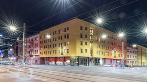 Un edificio de varios pisos con fachada amarilla, múltiples ventanas y acceso en la planta baja.