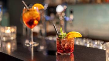 Two cocktails on a bar counter with a blurred background.