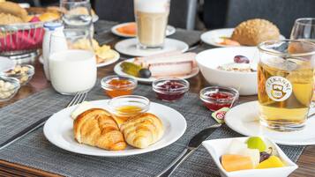 A breakfast setting with croissants, a glass of beer, and various condiments on a table.