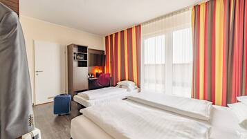 A hotel room with two beds, a desk with a computer, a minibar, and a window with curtains.