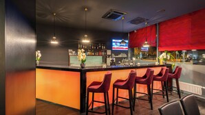 Zona de bar con mostrador, taburetes y una pantalla de televisión.