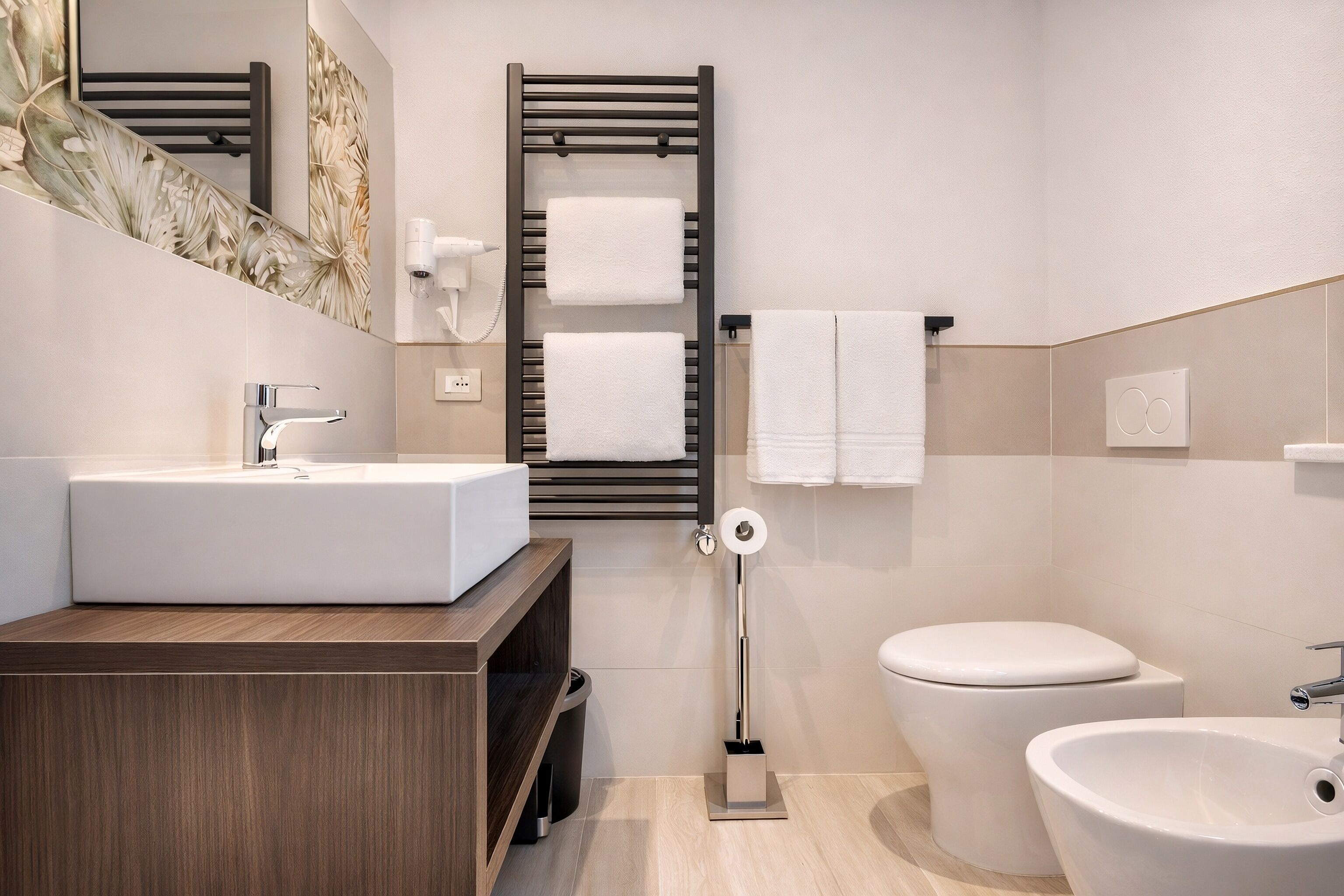 Un baño moderno con tocador de madera, un espejo grande, un perchero, un inodoro y un bidé.