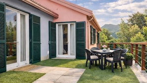 A patio with a table and chairs, a door, and a view of a mountain. - Hotel Del Borgo (Sestri Levante)