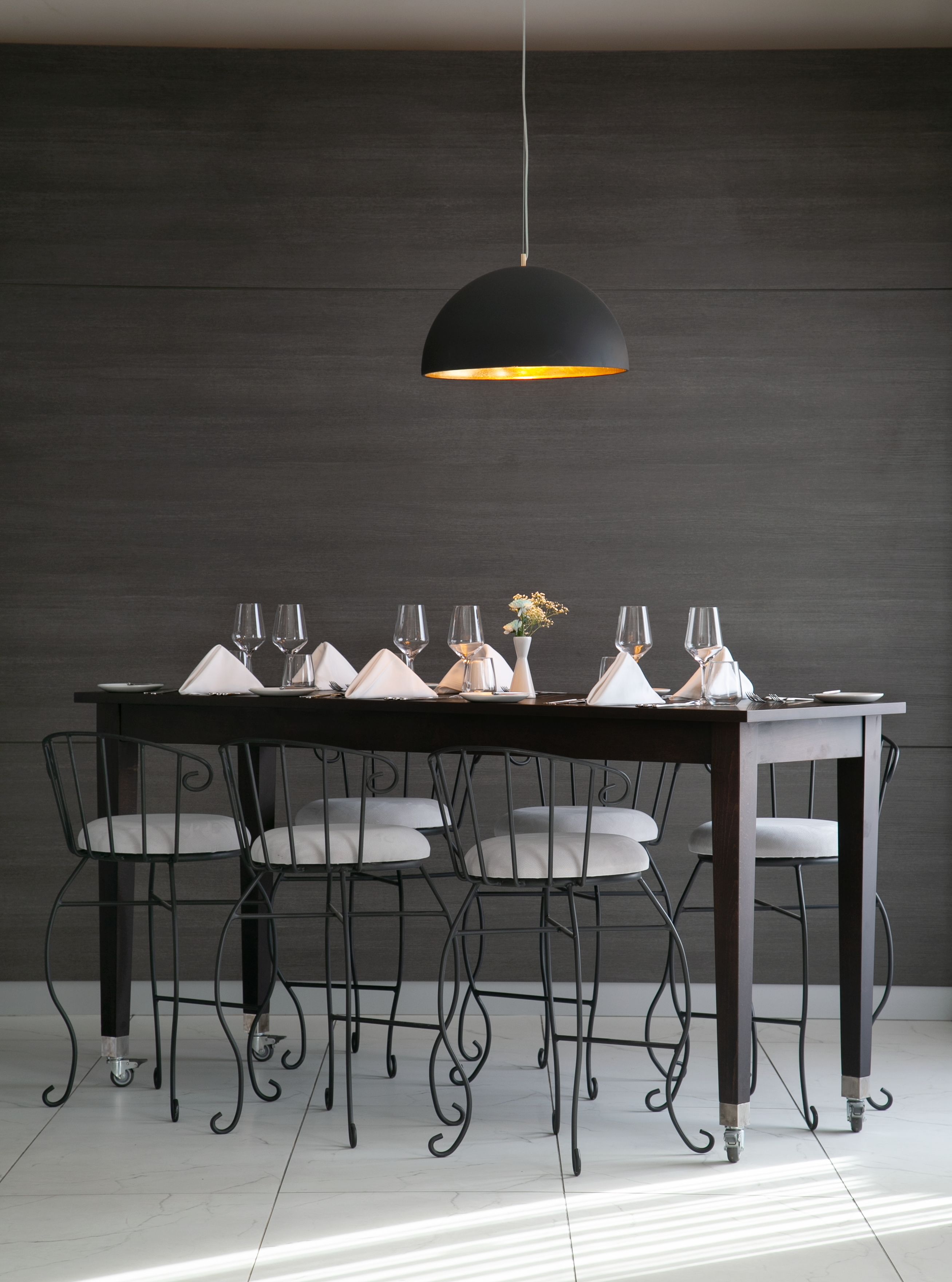 A dining table with six chairs, a vase with flowers, and a pendant light.