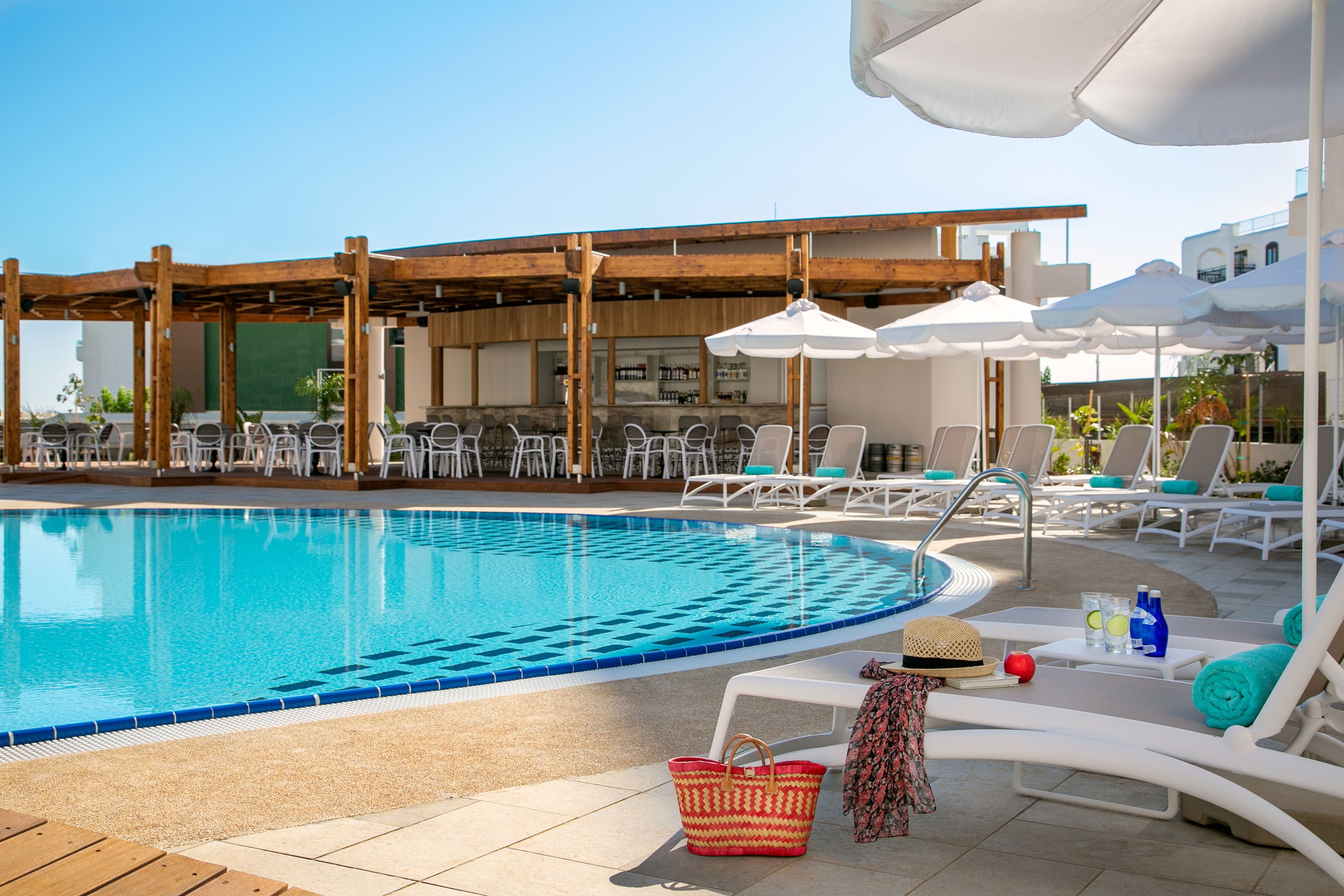 A poolside area with lounge chairs, umbrellas, and a bar.