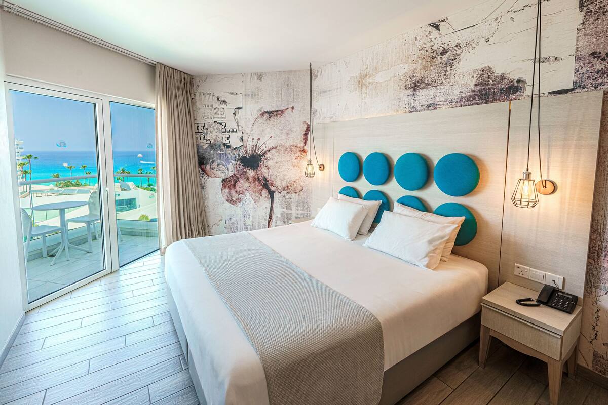 Une chambre d’hôtel avec un grand lit, une table de chevet et une vue sur la plage.