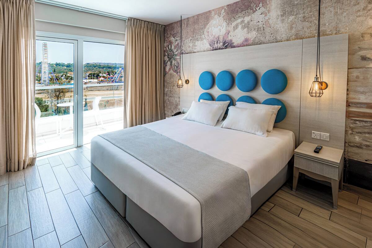 Une chambre d’hôtel moderne avec un grand lit, une vue sur la ville et un balcon.