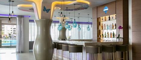 A modern bar area with a large vase, hanging pendant lights, and a bar counter with stools.