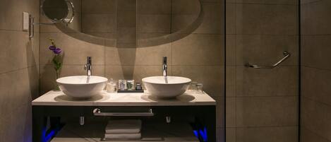 A modern bathroom with two sinks, a mirror, and a shower area.