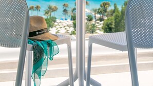 A balcony with two white chairs, a round table with two champagne glasses and a bowl of strawberries, and a straw hat on one chair. - Vangelis Hotel & Suites (Paralimni)