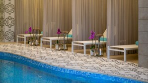 A poolside area with a tiled floor, white lounge chairs, and a pool. - Vangelis Hotel & Suites (Paralimni)